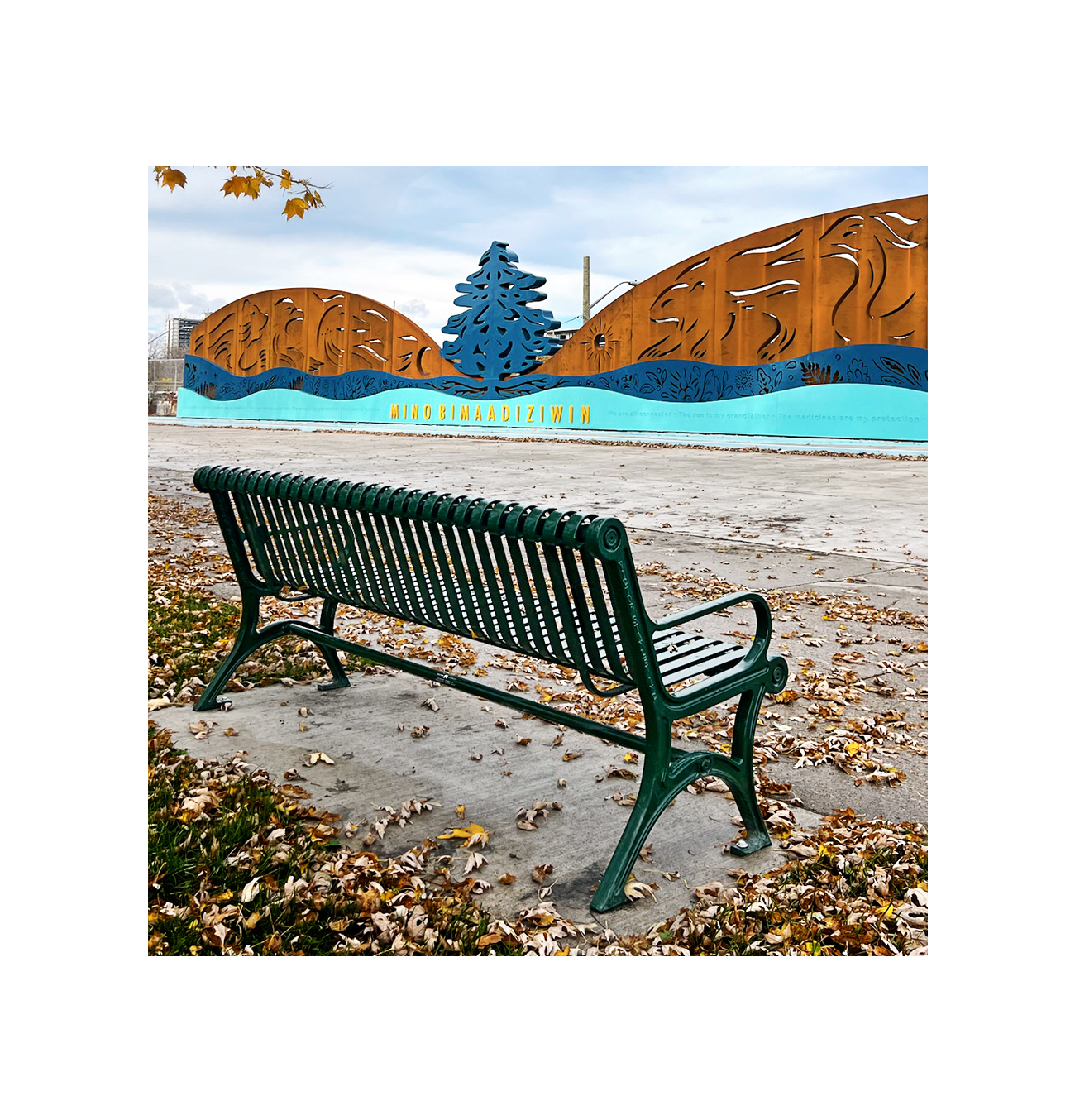 A classic Victor Stanley bench installed in front of an art mural at Exhibition Place in Toronto.