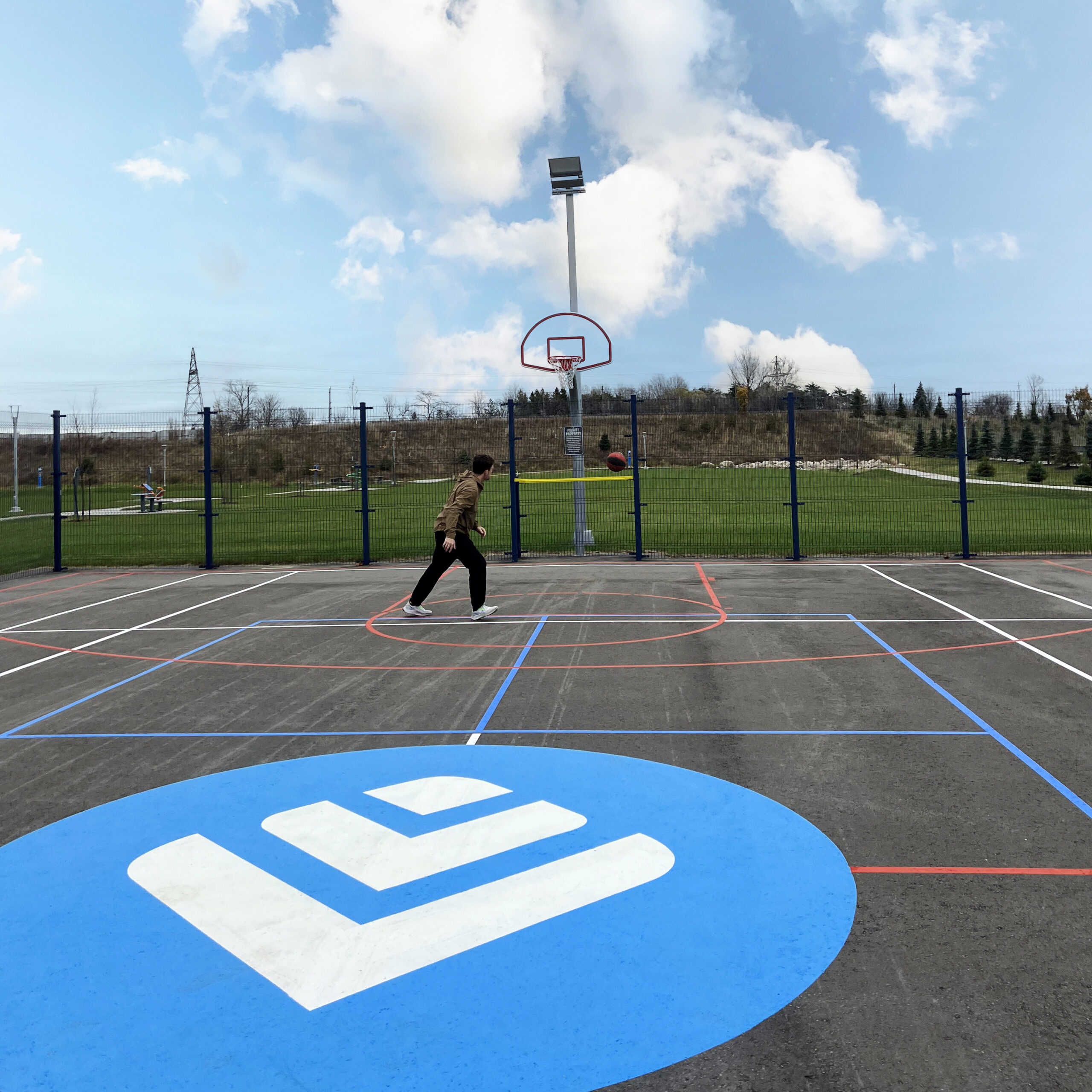 An person playing basketball on a court enclosed with Omega Architectural fence at the Co-operators head office in Guelph.